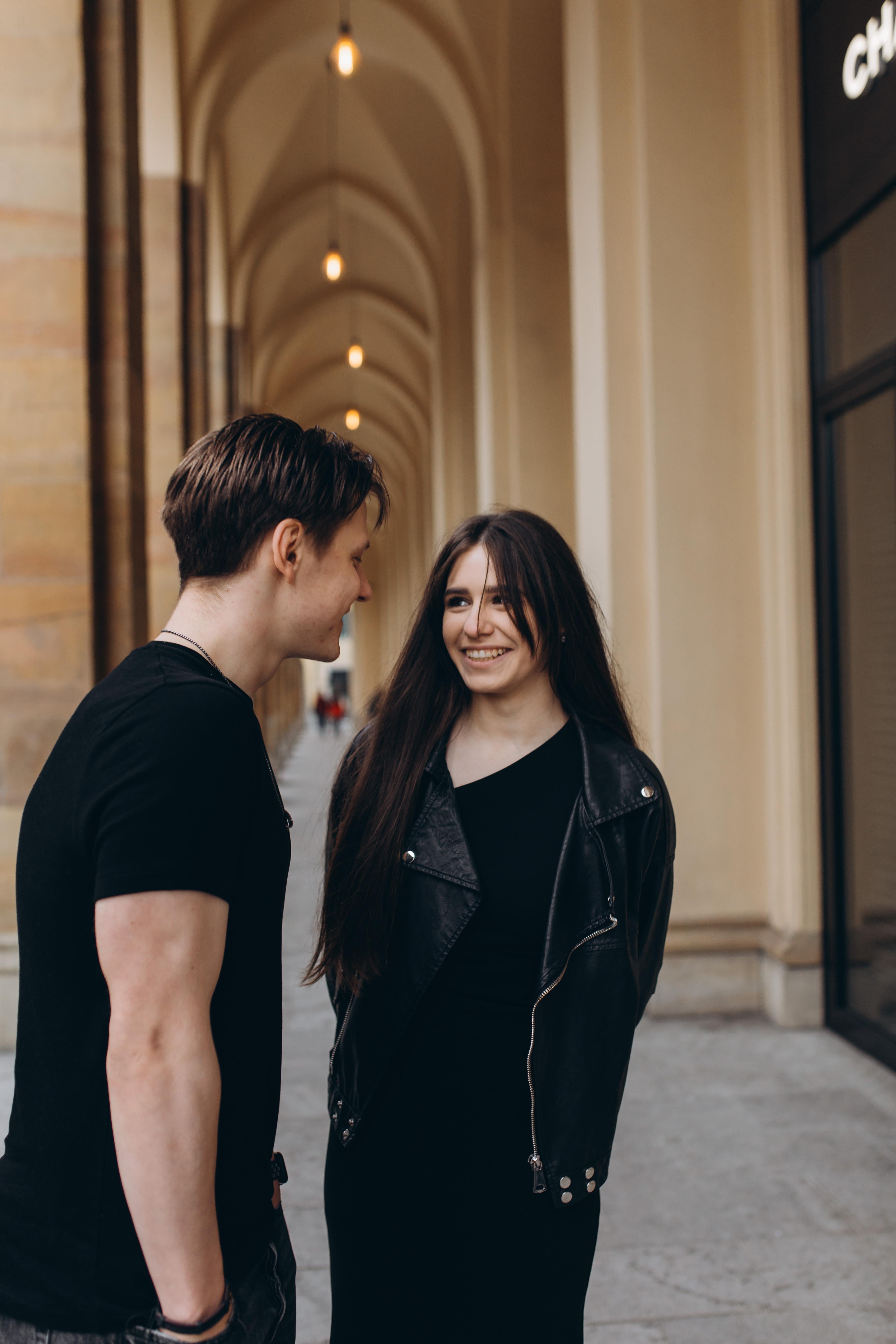 Two people standing close together in an archway, smiling at each other.