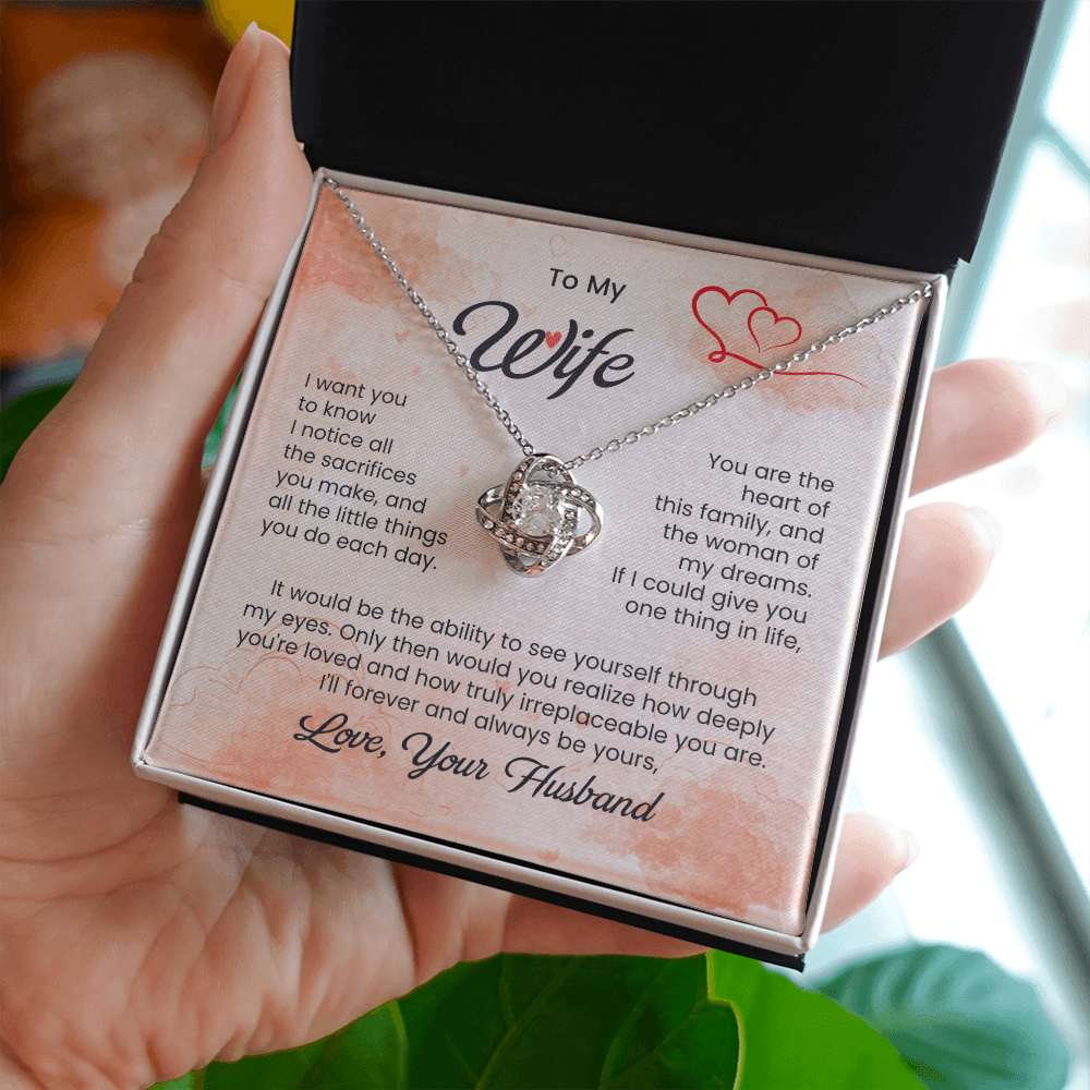 Necklace in a box with a sentimental message for a wife, held by a hand.