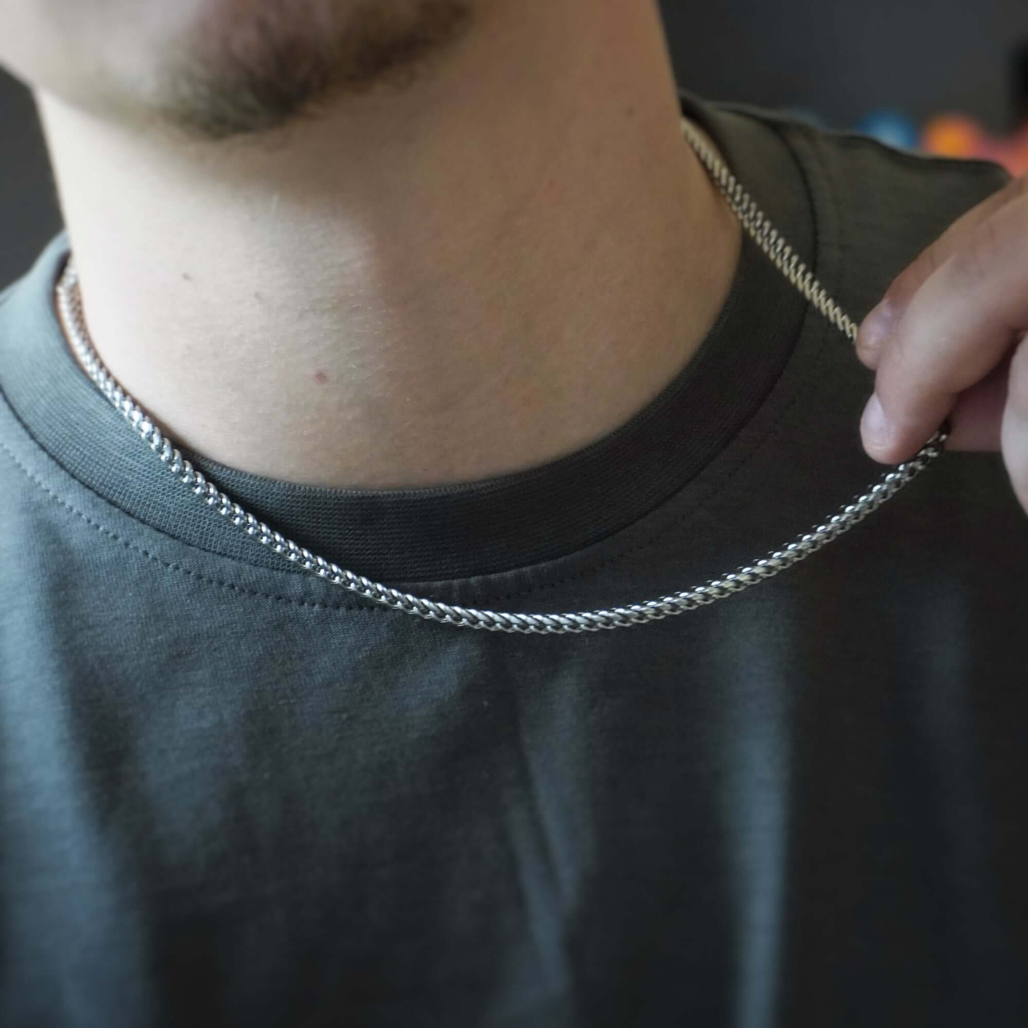 Person adjusting a silver chain necklace.