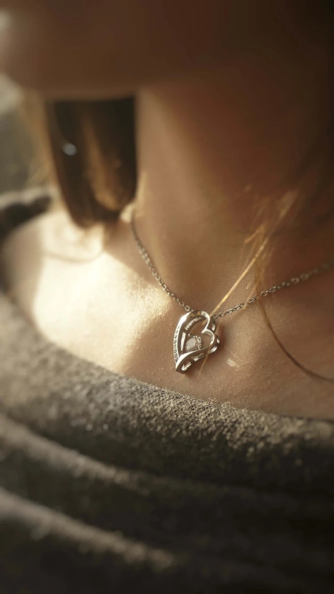 Close-up of a silver necklace with a heart-shaped pendant on a blurred background