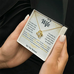 Gold necklace in a box with a sentimental message card held by hands.