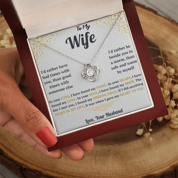 Necklace with a sentimental message card held by a hand on a wooden surface.